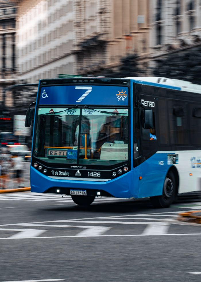 Blue public bus number 7 traveling on an urban street, representing city transportation.